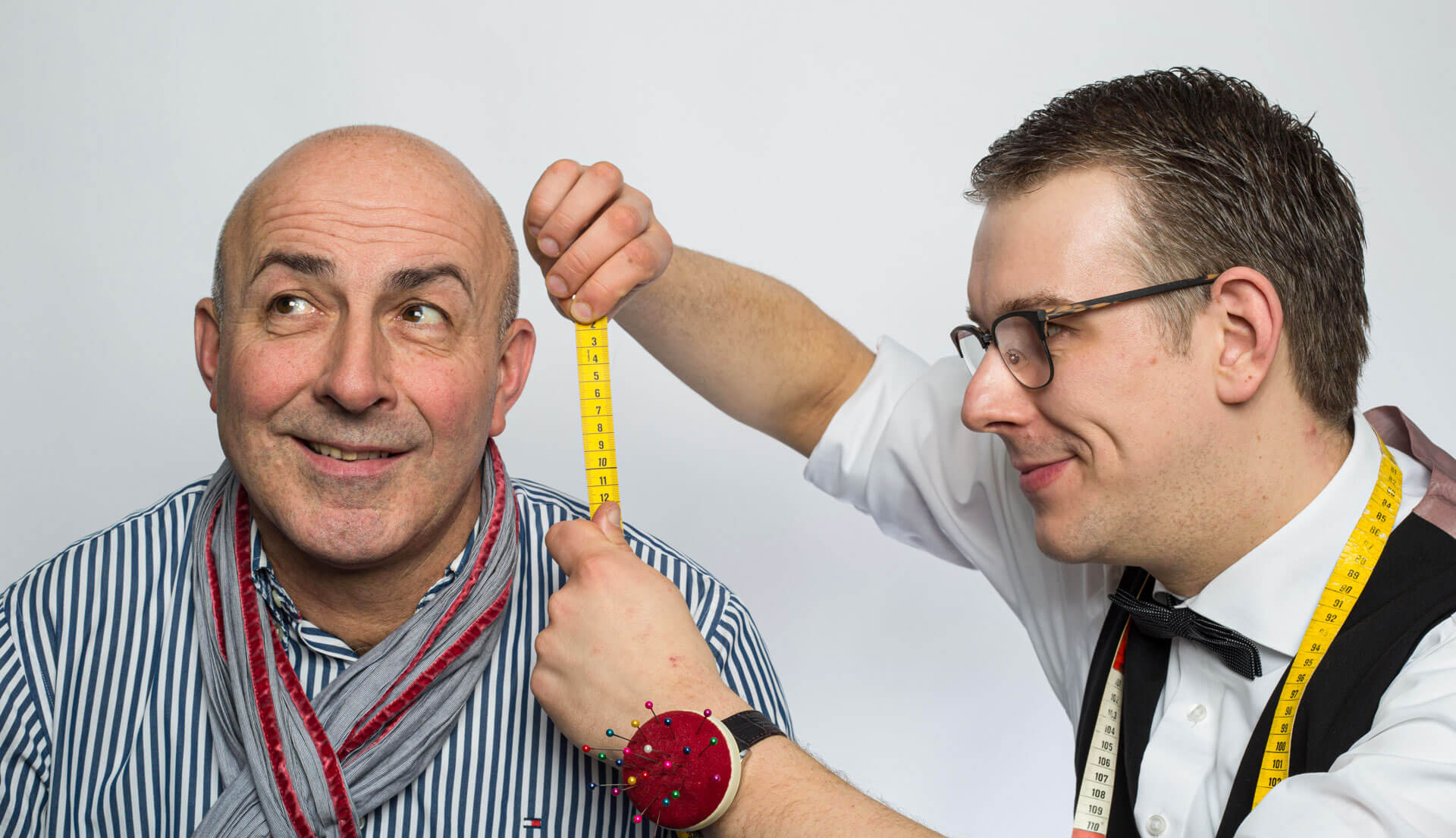 Sven Winkler misst symbolisch die Länge des Ohres eines Kunden.