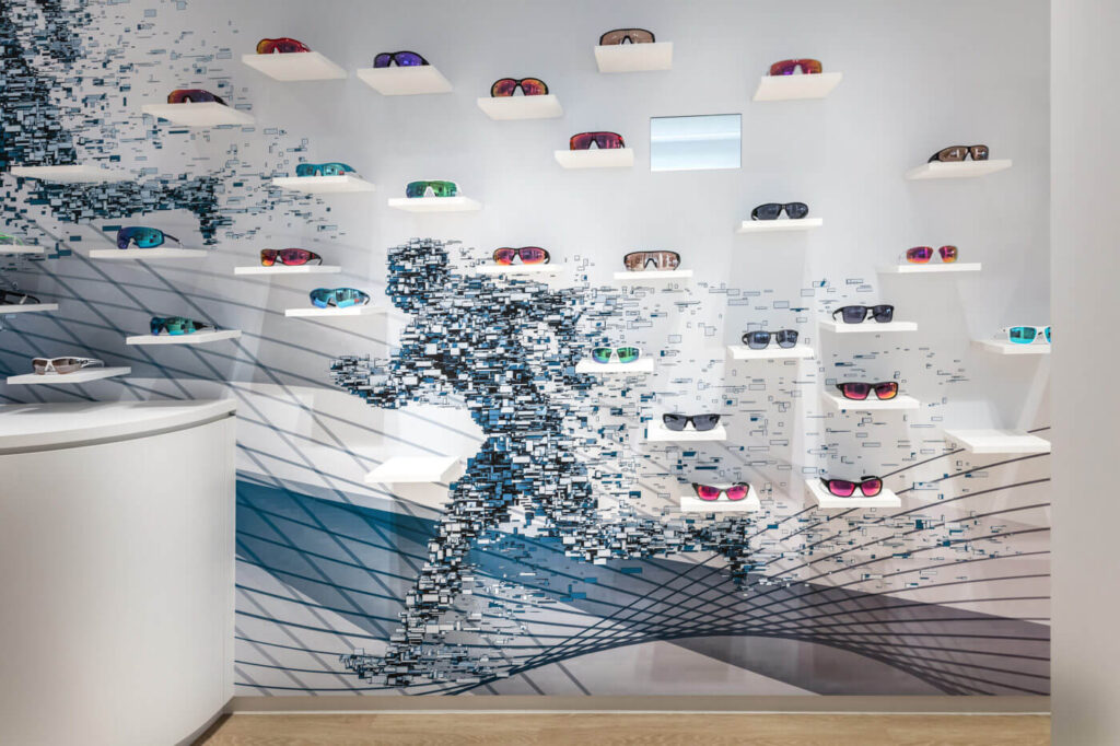 Aufnahme einer Wand aus der Filiale in Wittlich, an der eine große Auswahl an Sportbrillen präsentiert wird.