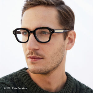 Junger Mann trägt eine schwarze Brille von der Marke Etnia Barcelona.