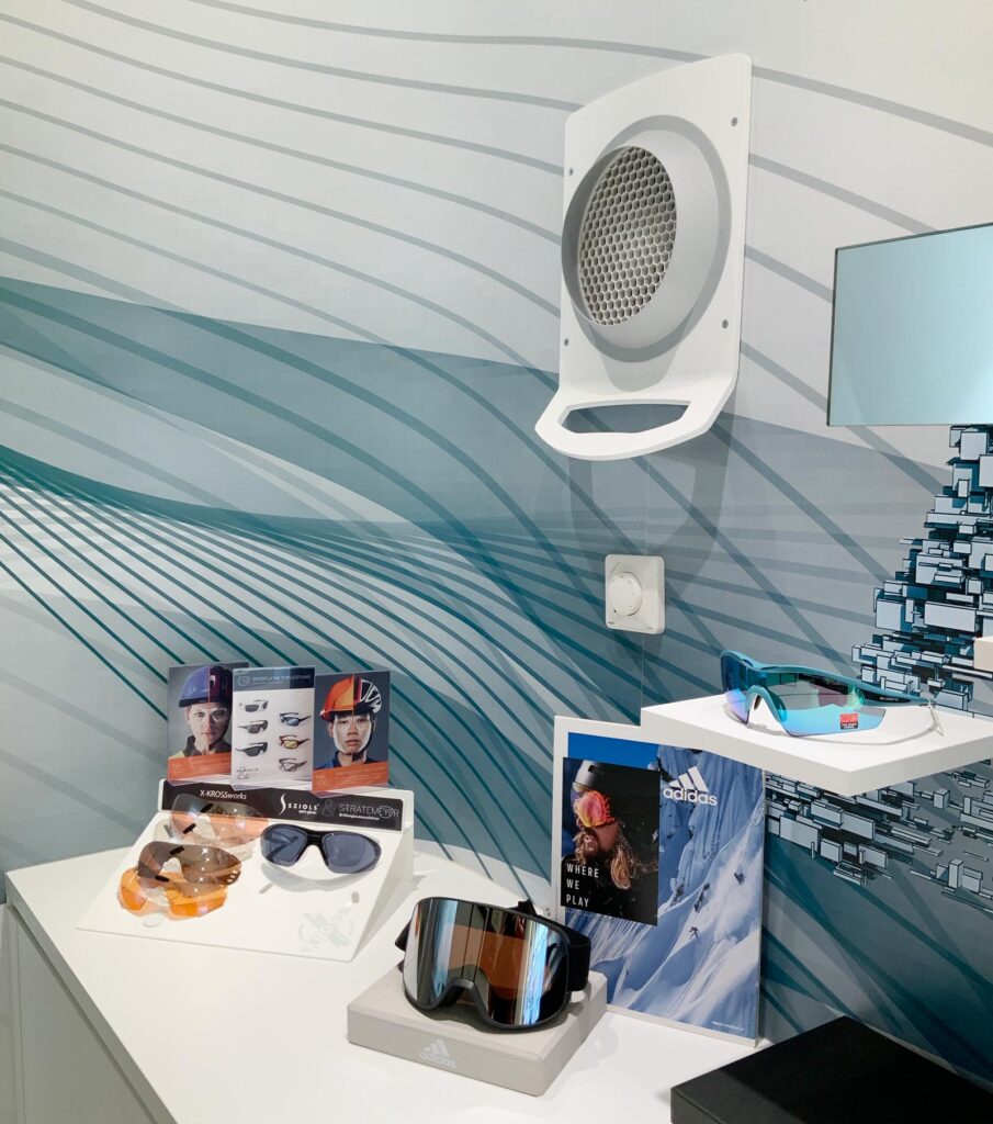 Strömungskanal in der Wand. Im unteren Bereich stehen zwei Displays mit Sportbrillen