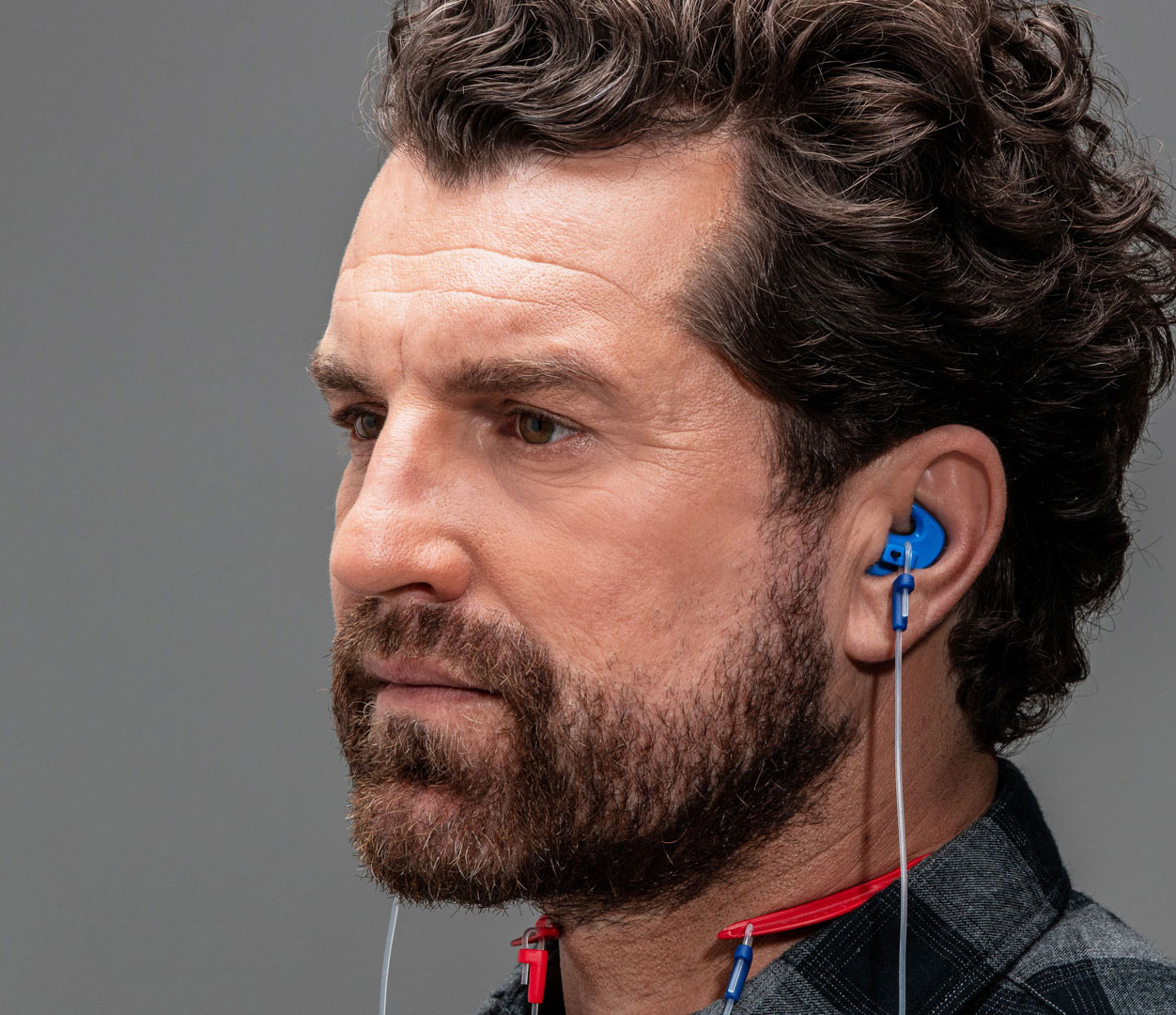 Profil eines Mannes mittleren Alters, der einen Gehörschutz in den Ohren trägt.