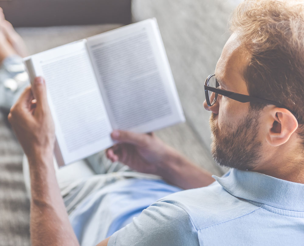 Mann mit Brille blickt auf ein Buch