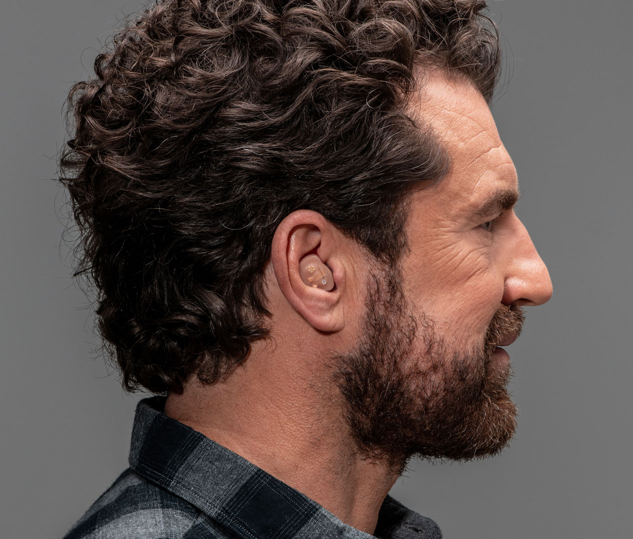 Profil eines Mannes mittleren Alters, der einen Gehörschutz im Ohr trägt.