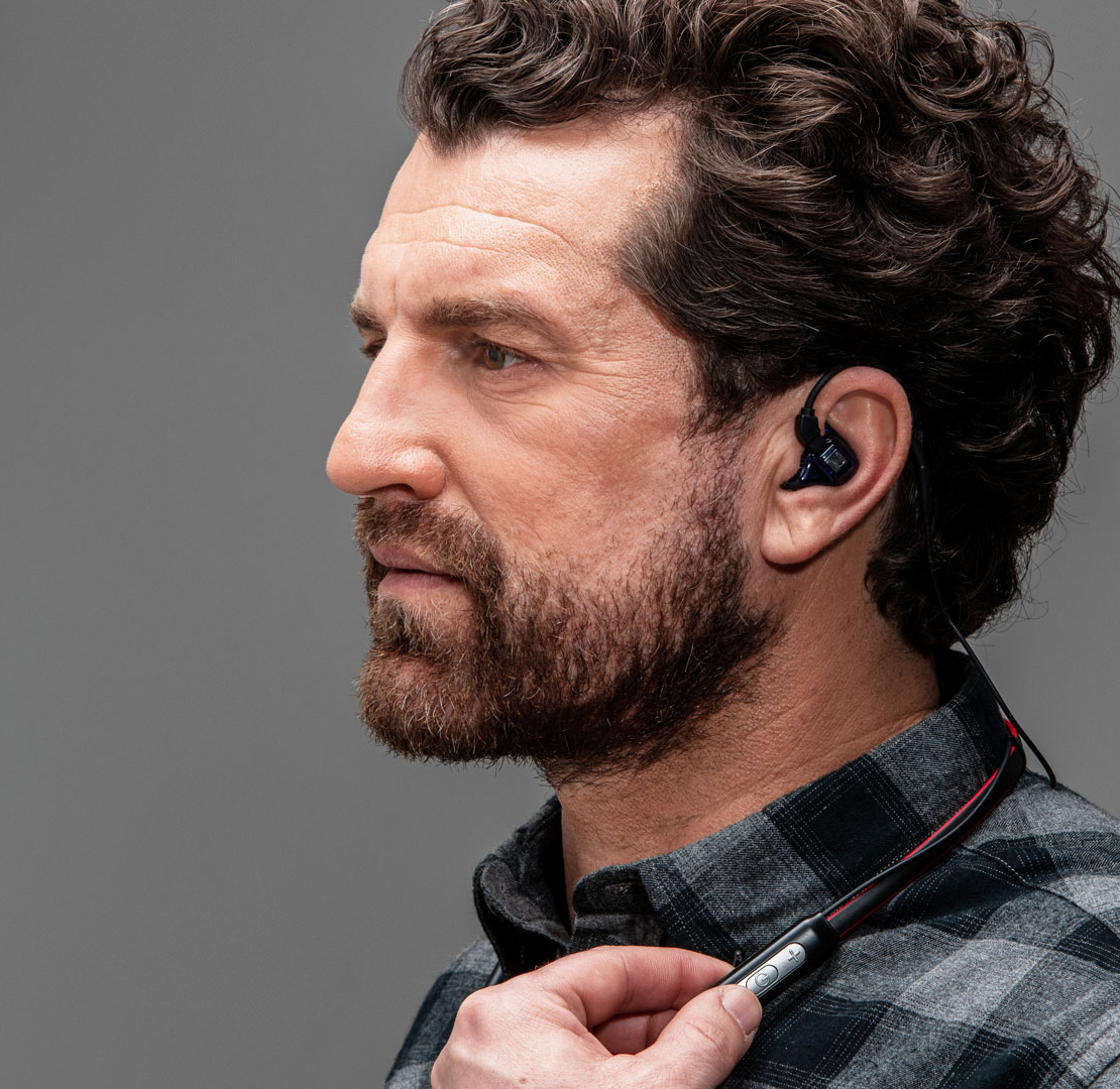 Profil eines Mannes mittleren Alters, der einen Gehörschutz mit Sprachfunktion im Ohr trägt.