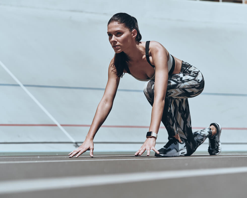 Läuferin in Startposition auf einer Laufbahn