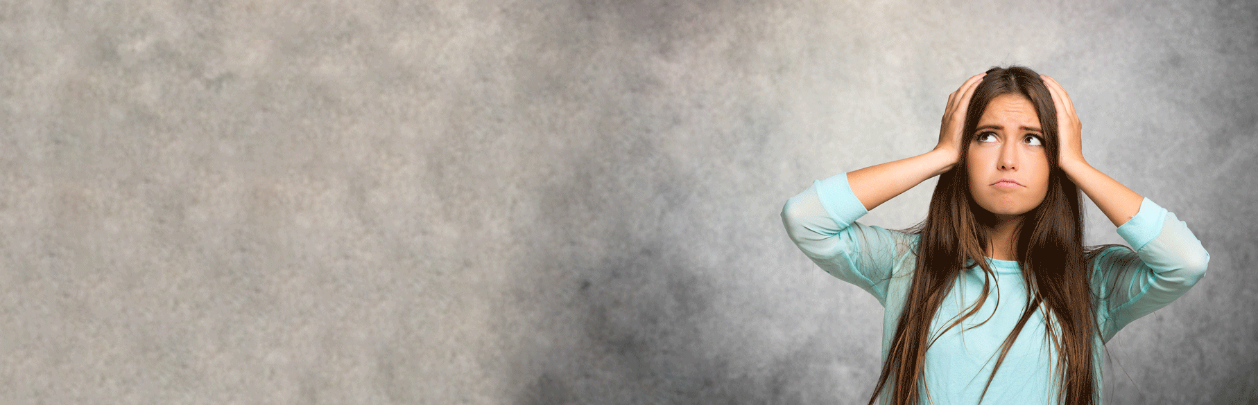 Aufnahme einer jungen Frau, die sich fragend an den Kopf mit beiden Händen fasst