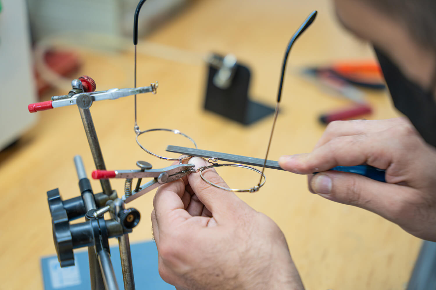 Ein Brillengestell, welches von einem Optiker mit einer kleinen Pfeile bearbeitet wird