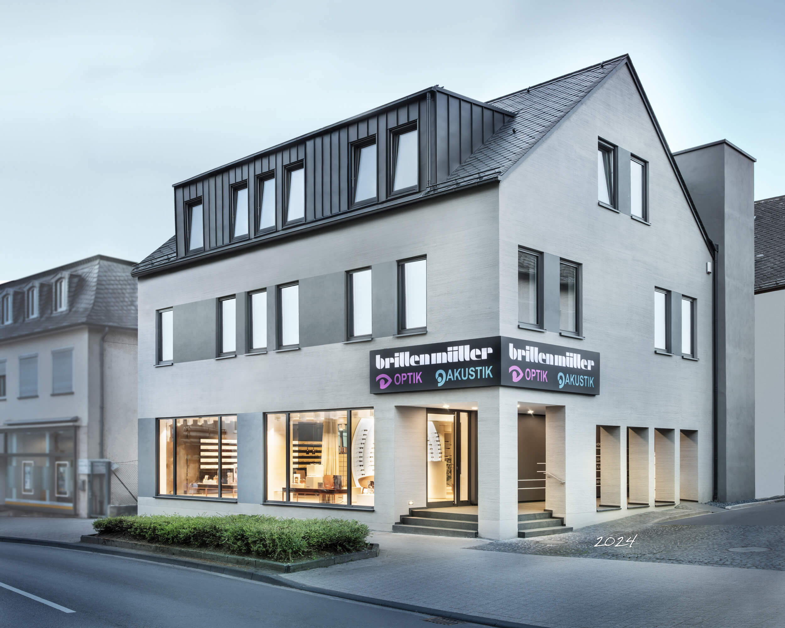 Weitwinkel-Aufnahme des Brillen Müller Gebäudes in Wittlich, das Schaufenster ist beleuchtet